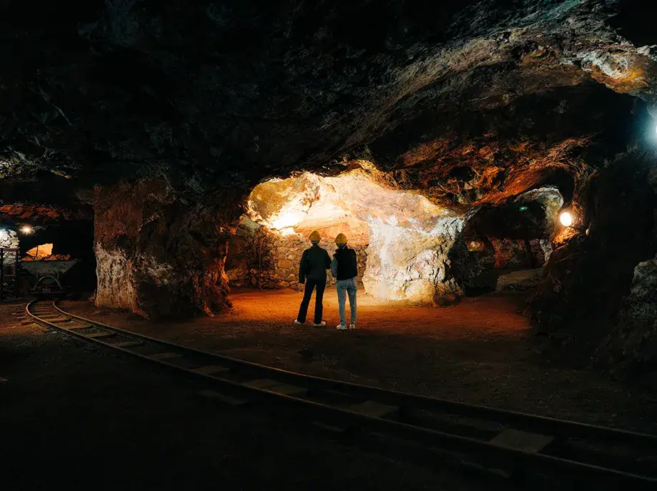 Dos visitantes en una amplia cavidad interior de la mina del Parc Miner del Maestrat